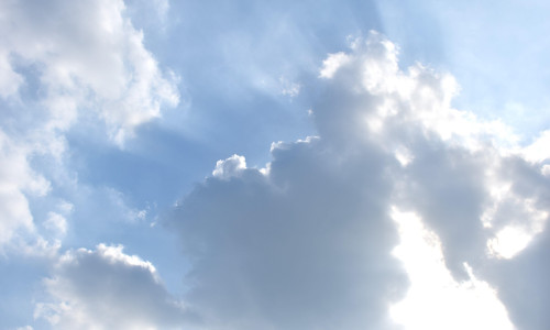 sunlight spreading from dark rain cloud floating on sky in afternoon