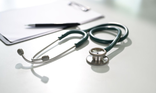 Stethoscope on a white desk with clipboard symbolizing diagnostics, and healthcare concept