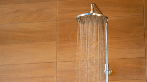 Outdoor shower head for the bath and showering cold water to body before jumping in the resort pool.