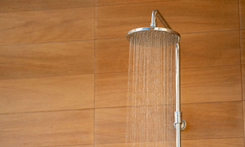 Outdoor shower head for the bath and showering cold water to body before jumping in the resort pool.