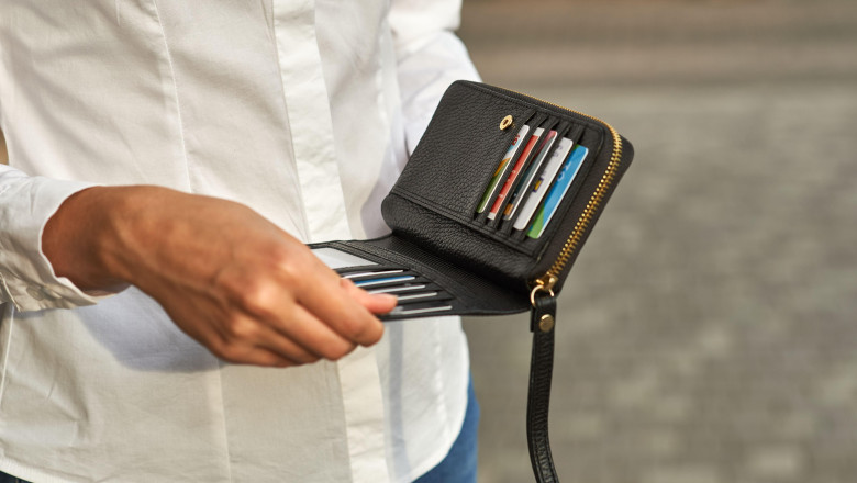 Close-up of hand holding black wallet with several credit cards inside, showcasing detail, business and finance theme