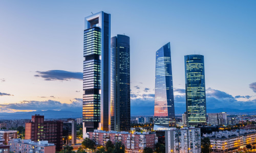 Cityscape of Madrid’s financial district at dusk, featuring modern skyscrapers illuminated against the fading evening sky. This area on the North of t