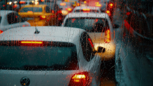Bucharest, Romania - January 11, 2023: Cars in traffic at rush hour waiting at the red traffic light during the rain on a boulevard in Bucharest.