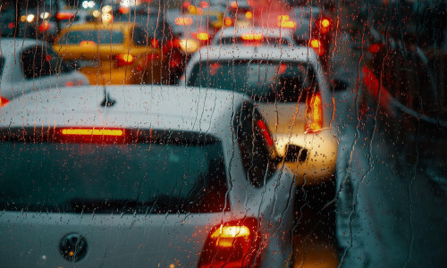 Bucharest, Romania - January 11, 2023: Cars in traffic at rush hour waiting at the red traffic light during the rain on a boulevard in Bucharest.