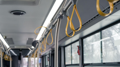 Interior of a empty bus with many hand holders or grips on the handle bar