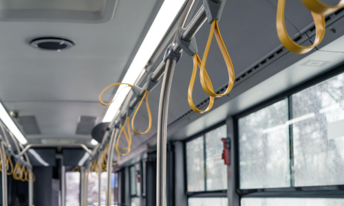 Interior of a empty bus with many hand holders or grips on the handle bar