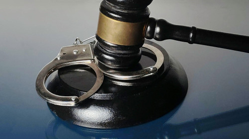 Handcuffs Resting on Gavel Base with Judge's Mallet Symbolizing Crime and Law Enforcement
