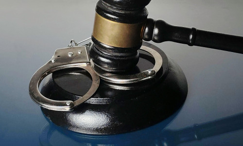 Handcuffs Resting on Gavel Base with Judge's Mallet Symbolizing Crime and Law Enforcement