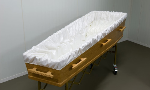An empty coffin with white sheet in a morgue