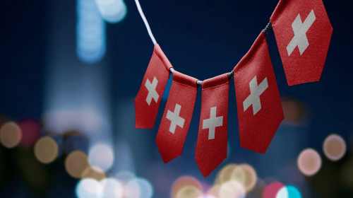 A garland of Switzerland national flags on an abstract blurred background.