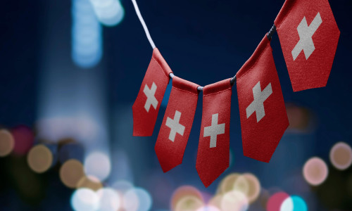 A garland of Switzerland national flags on an abstract blurred background.