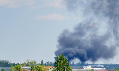 Black heavy smoke cloud near apartment building in residential area of Bucharest, Romania, on a sunny Spring day.