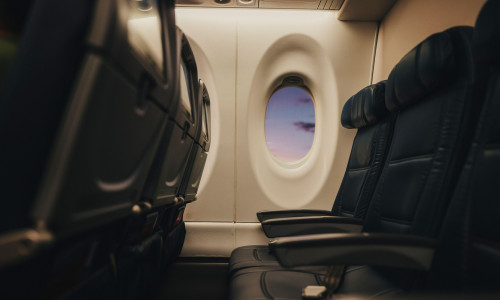Soft light falls across empty airplane seats at the window.