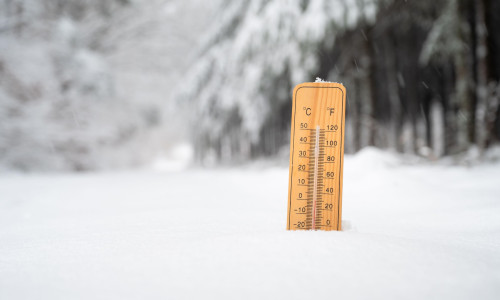 Thermometer in snow covered landscape, cold frosty weather forecast in winter, measure the temperature