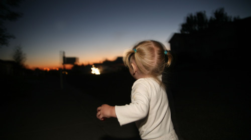 Toddler walking down sidewalk at night.