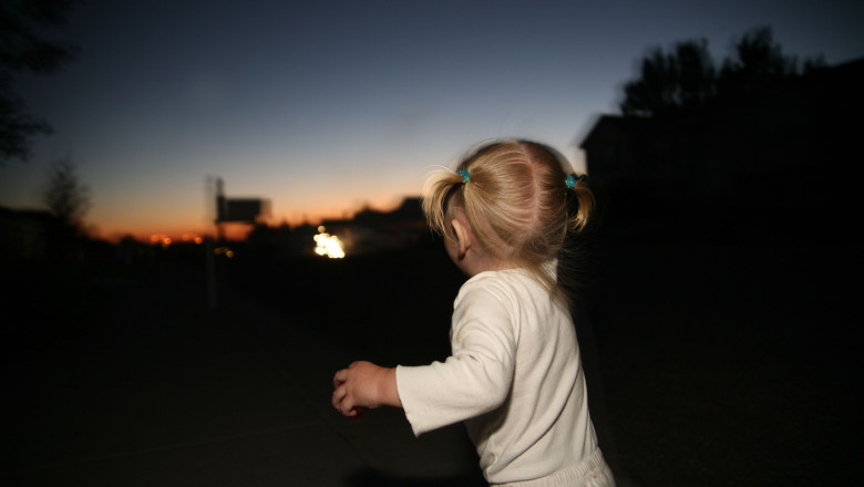 Toddler walking down sidewalk at night.