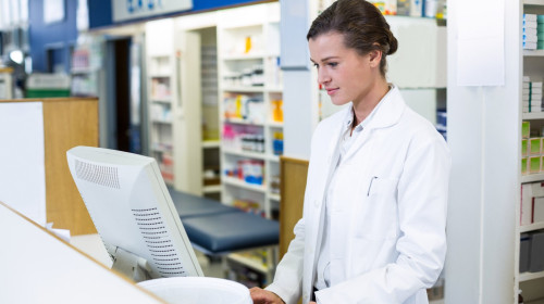 Pharmacist making prescription record through computer in pharmacy