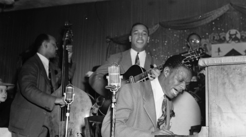 Nat King Cole (piano) playing at Zanzibar Club in New York with Wesley Prince, and Oscar Moore in July 1946. Nathaniel Adams Coles (March 17, 1919 – February 15, 1965),known professionally as Nat King Cole, was an American singer, jazz pianist, and actor.
