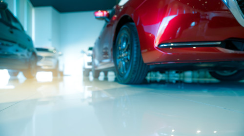 Blurred red and white car parked in modern showroom. Car dealership and auto leasing concept. Automotive industry. Modern luxury showroom. New car global market trends topics background.