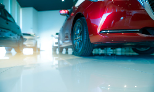 Blurred red and white car parked in modern showroom. Car dealership and auto leasing concept. Automotive industry. Modern luxury showroom. New car global market trends topics background.