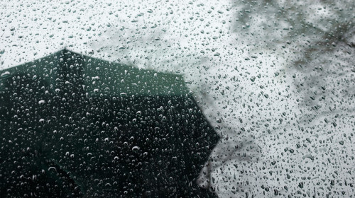 rainy weather reflections in car window. man with an umbrella under rain. bad weather.