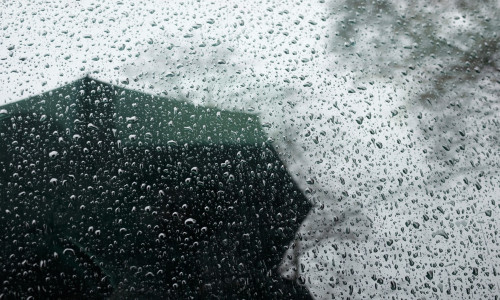 rainy weather reflections in car window. man with an umbrella under rain. bad weather.
