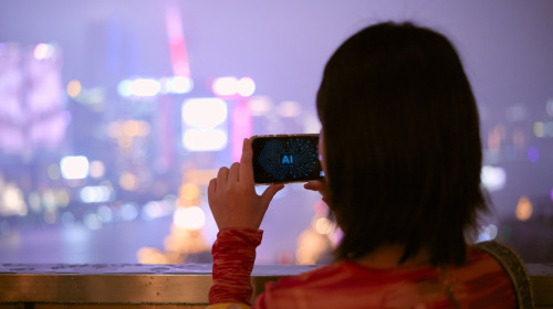 Woman capturing cityscape on AI phone at night with vibrant lights in the background. Shanghai, China