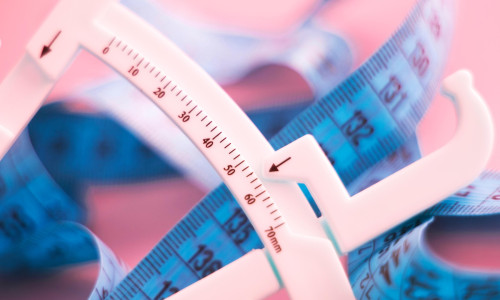 Fat caliper and measuring tape used to measure waistline, bodyfat levels for fitness and obesity checks.