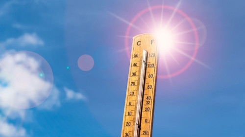 Thermometer against blue sunny sky. Hot summer weather concept.