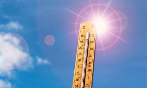 Thermometer against blue sunny sky. Hot summer weather concept.