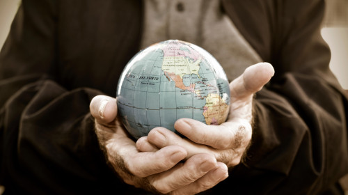 closeup of an old caucasian man with a world globe in his hands, with a dramatic effect