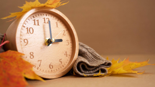 Wooden clock with autumn leaves indicating time change