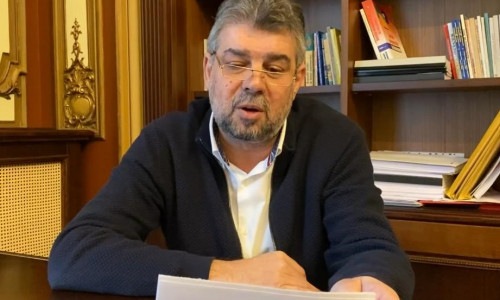 Marcel Ciolacu, citește de pe foi lângă o bibliotecă