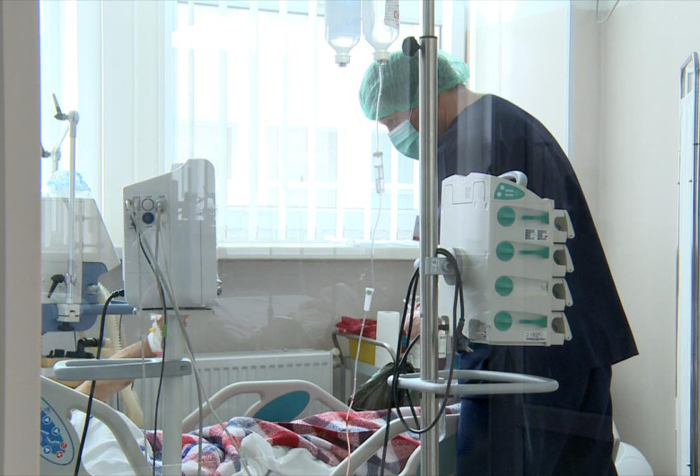 Pacient pe pat de spital cu doctor lângă el