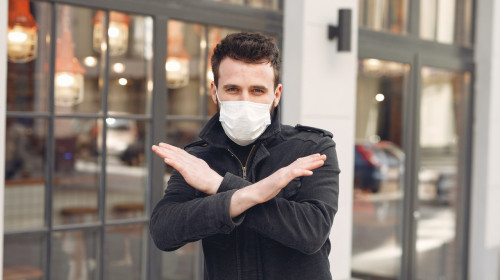 Bărbat tânăr cu mască sanitară pe față anti COVID-19, coronavirus, zâmbitor