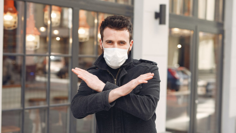 Bărbat tânăr cu mască sanitară pe față anti COVID-19, coronavirus, zâmbitor