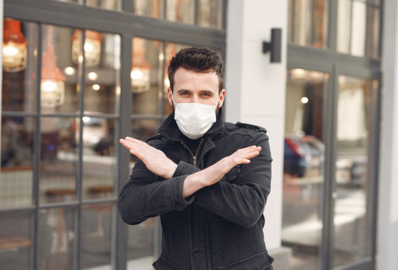 Bărbat tânăr cu mască sanitară pe față anti COVID-19, coronavirus, zâmbitor