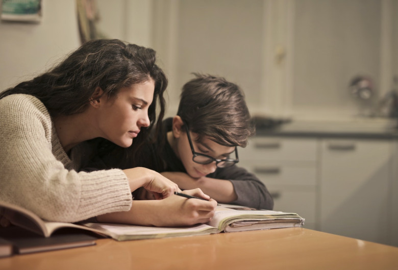 Părinte cu copil elev, școala acasă, femeie cu băiat învață, scrie, studii