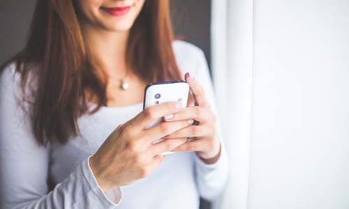 Femeie se uită la telefonul mobil, smartphone