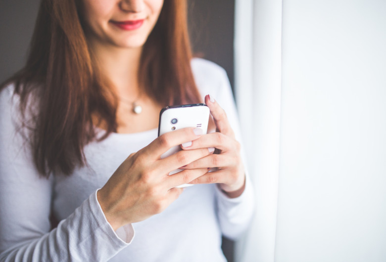 Femeie se uită la telefonul mobil, smartphone