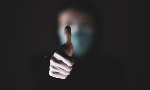 Om cu mască de protecție împotriva COVID-19, coronavirus arată cu degetul de OK, totul va fi bine