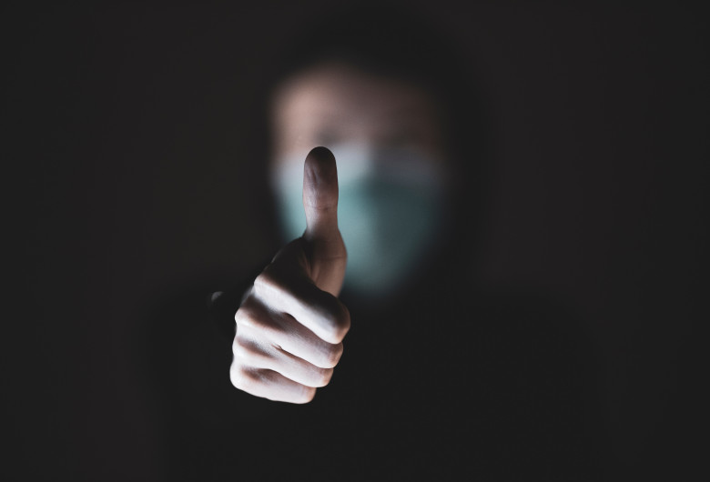 Om cu mască de protecție împotriva COVID-19, coronavirus arată cu degetul de OK, totul va fi bine