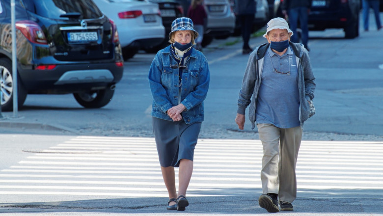 Doi bătrâni fac o plimbare pe o stradă goală, promenadă
