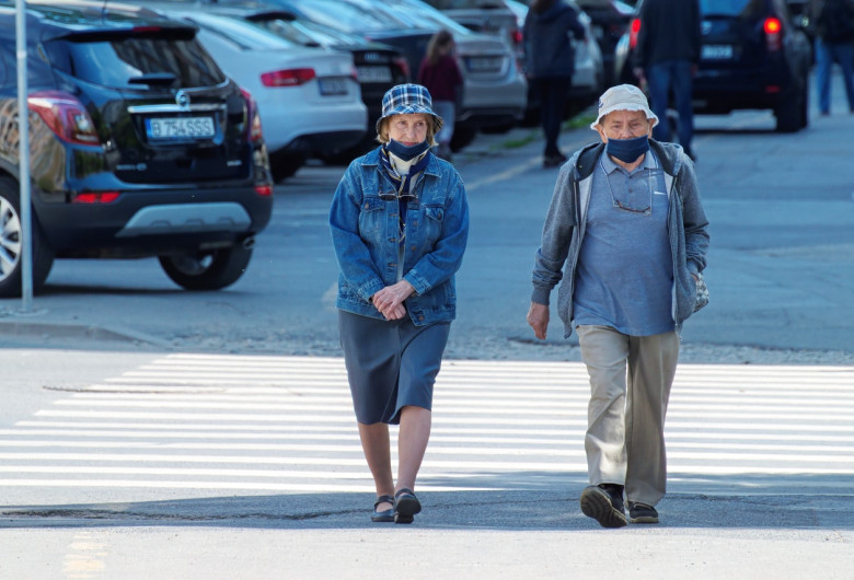 Doi bătrâni fac o plimbare pe o stradă goală, promenadă