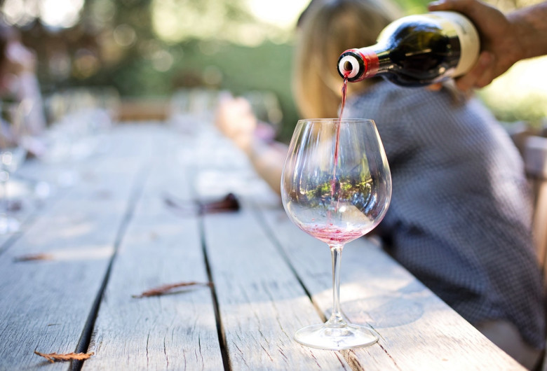 Vin turnat în pahar pe o terasă de vară, băutură, relaxare, alcool