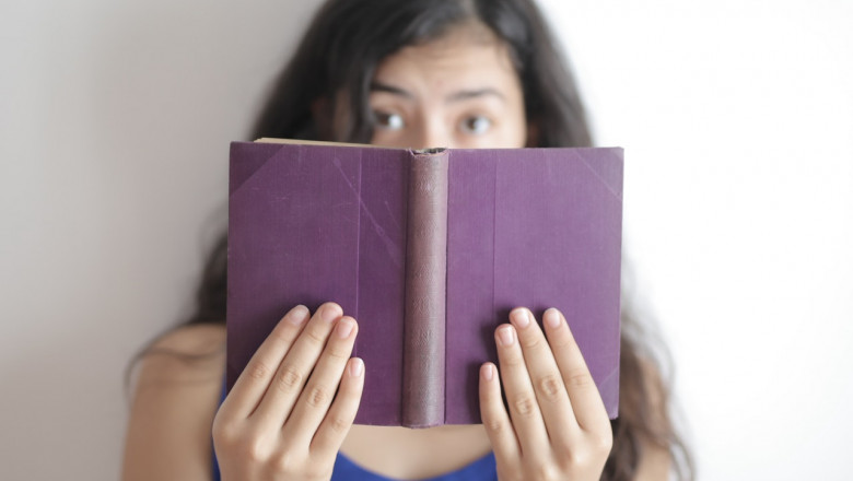 Fată care se uită mirată într-o carte, elevă, citit