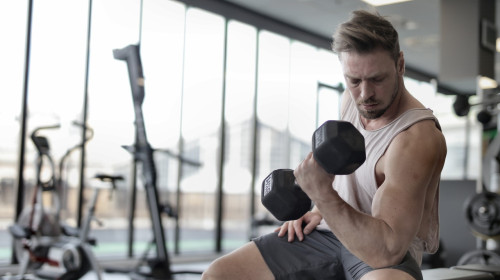 Bărbat trage de fiare în sala de fitness, sală de forță, gantere
