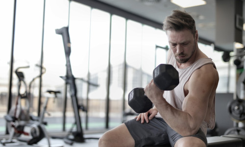 Bărbat trage de fiare în sala de fitness, sală de forță, gantere