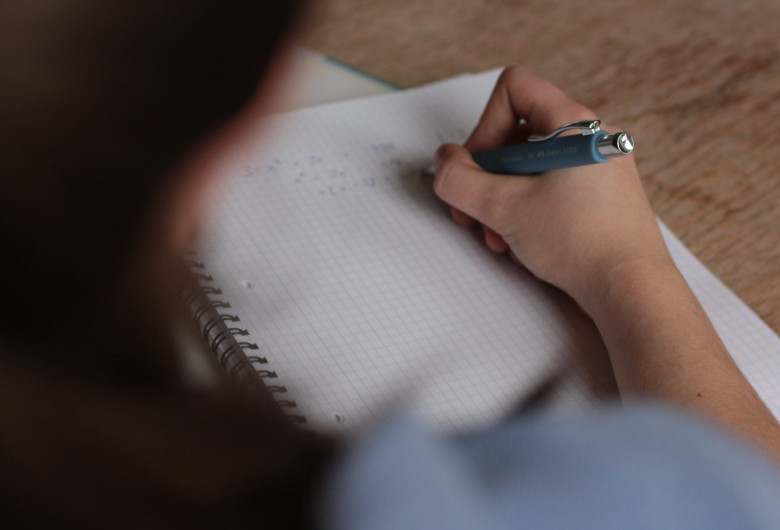Elevă scrie pe un caiet de matematică, școală, examen, test, evaluare