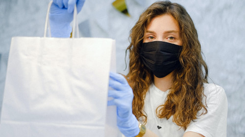 Tânără femeie cu plasă de cumpărături și mască de COVID-19, coronavirus